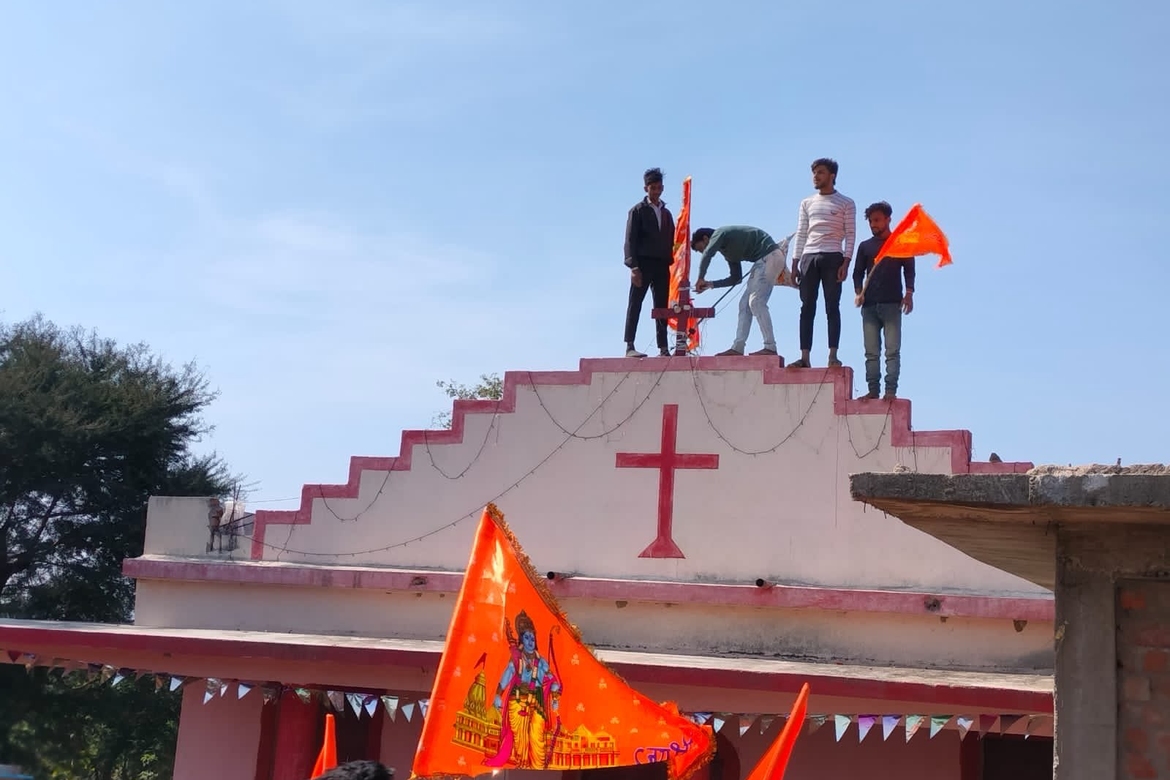 Hinduaktivister planter et saffran-farget flagg på en kirke i Ayodhya som del av feiringen av det nye hindutemplet i byen.