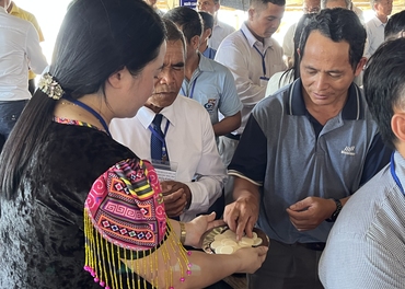 Dien, in traditional Hmong attire, offers communion to male pastors during a conference.