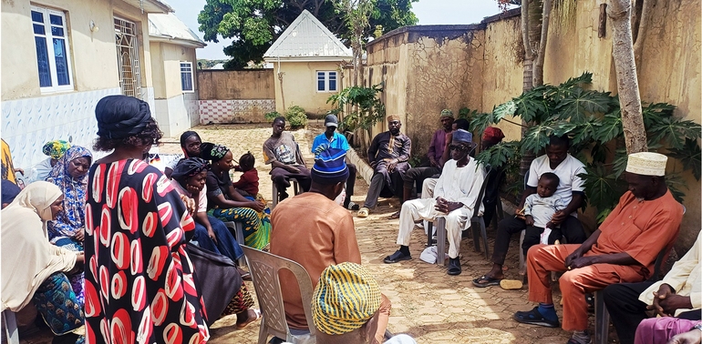 A group of African women and men sit in a circle.