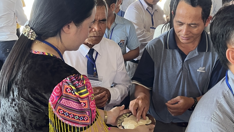 Dien, in traditional Hmong attire, offers communion to male pastors during a conference.